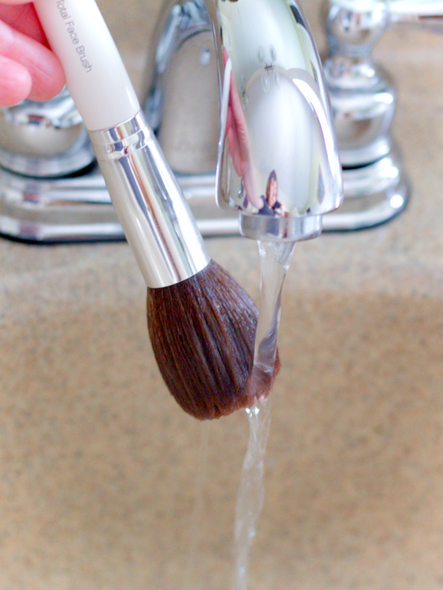 Rinsing The Makeup Brush Under Water To Get The Cleanser Out