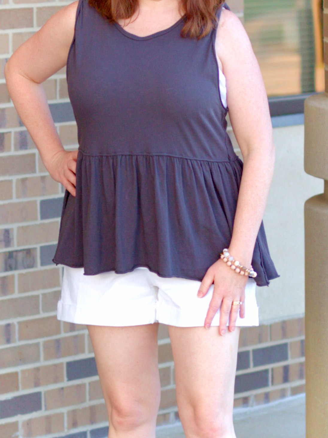 A Closeup Of The Peplum Top With Pink And Grey Bracelet